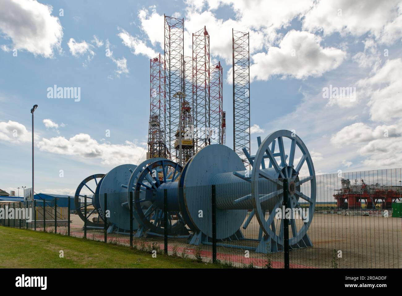 Grands rouleaux de câbles bleus au premier plan d'une zone de construction de plate-forme pétrolière à Invergordon, en Écosse. Jack Up Rig jambes en arrière-plan. Banque D'Images