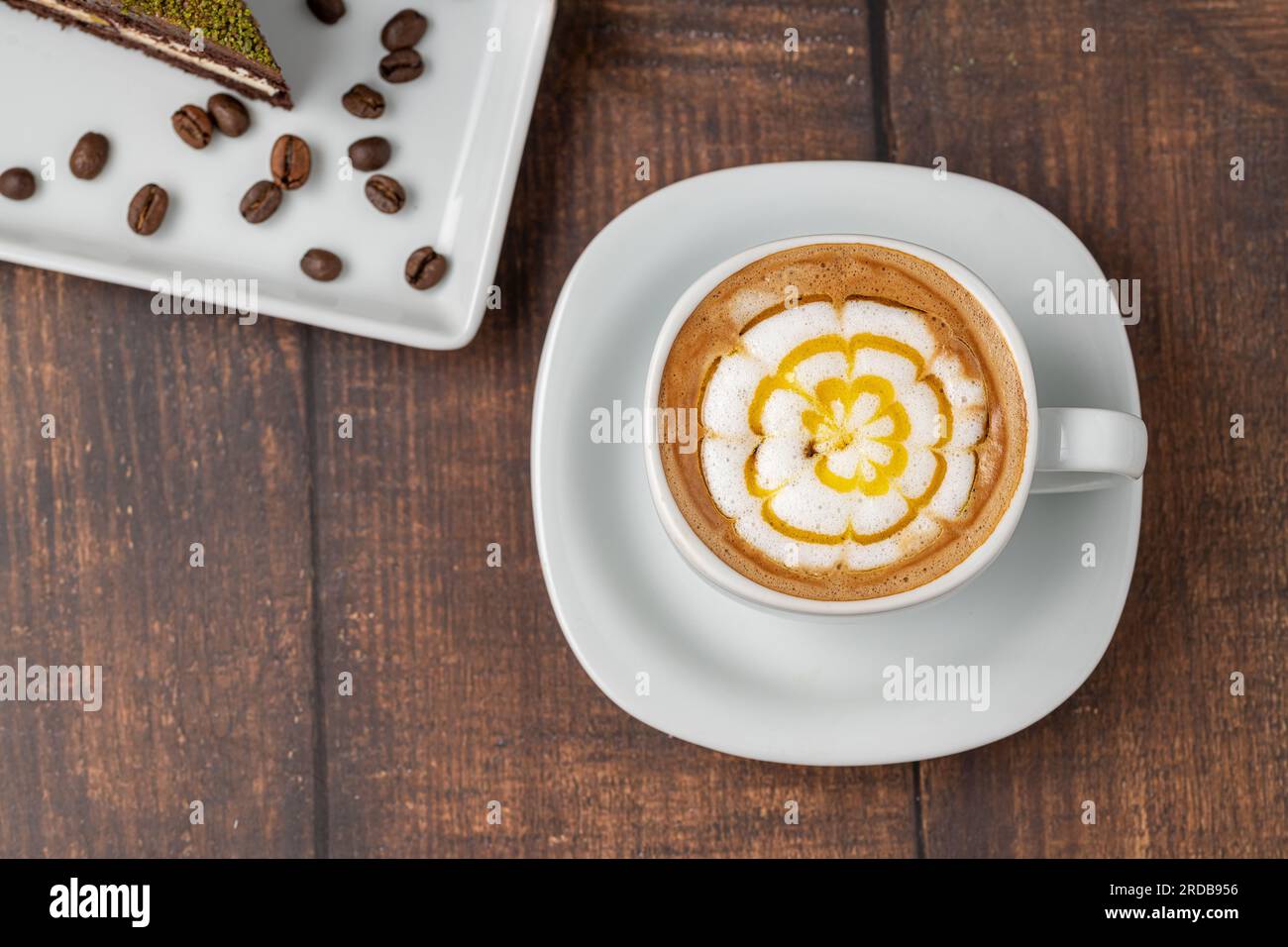 Café cappuccino à motifs dans une tasse en porcelaine blanche sur une table en bois Banque D'Images