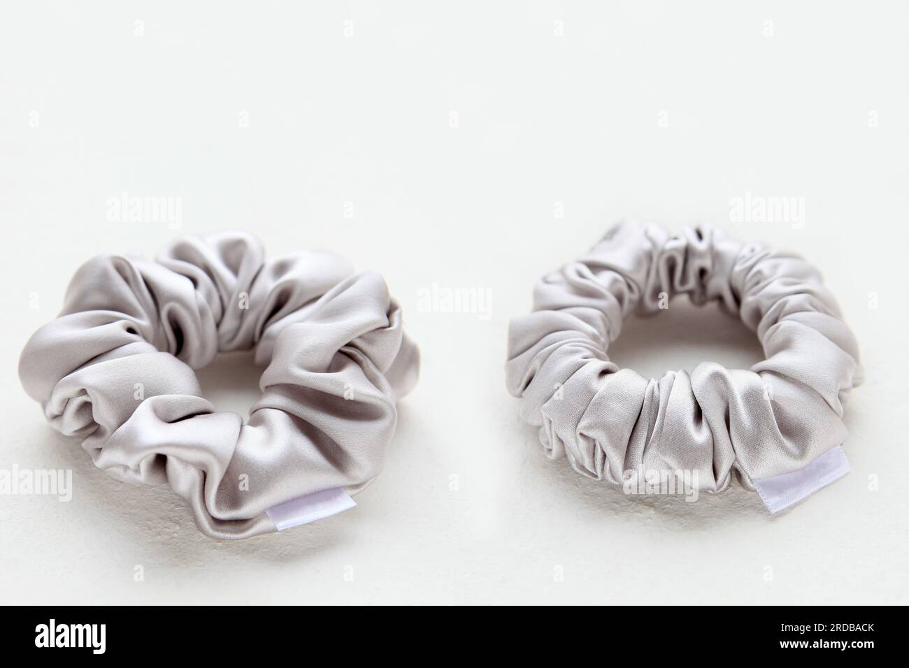 Soie argentée Scrunchy sur fond blanc. Outil de coiffure de bandeau coloré Elastic Bobble. Banque D'Images