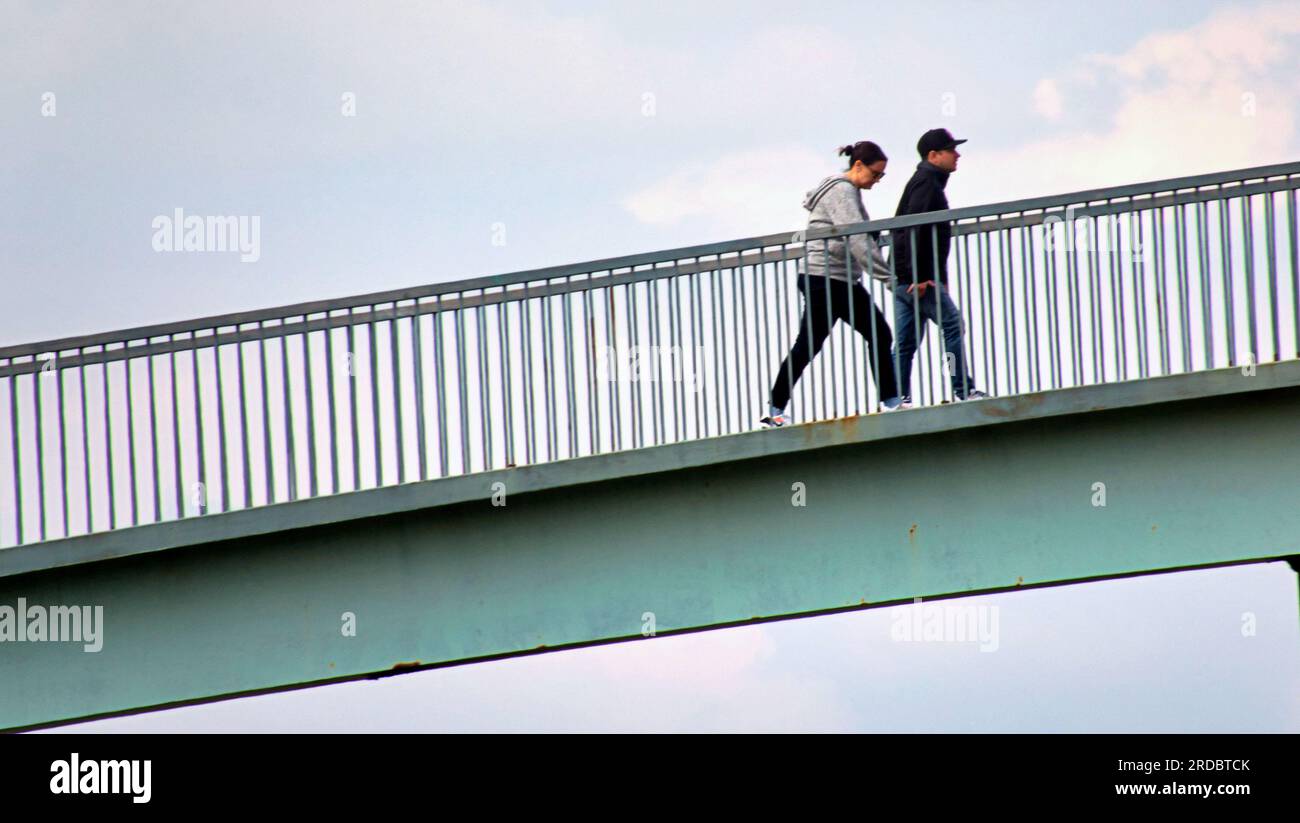 couple traverser un pont piétonnier sur la voie express clydeside Banque D'Images