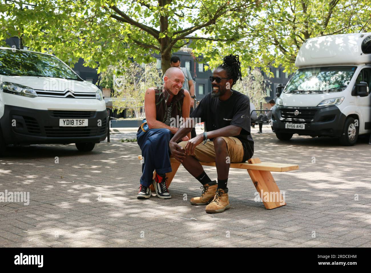 Londres, Royaume-Uni. 20 juillet 2023. 'Bench invasion' de la Compagnie Krak. Dans la performance 'Bench invasion', l'artiste belge Dieter Peter Raphaël Missiaen se déplace dans l'espace public avec dix personnes locales, chacune avec un banc sous le bras, à la recherche de contacts. À un moment inopiné, ils installent des bancs et invitent activement les gens à s’asseoir devant eux. De cette façon, il (re)connecte les gens. Le Festival d'ensemble est un festival de quatre jours de théâtre, de cirque, de danse, de musique et d'art numérique gratuits au Royal Victoria Dock. Ensemble Festival explore les thèmes de l'écologie, de la vie moderne et de la reconnexion, et comprend deux jours de pop-up per Banque D'Images