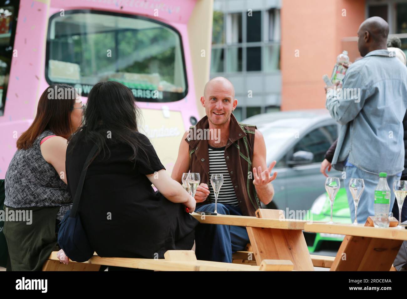 Londres, Royaume-Uni. 20 juillet 2023. 'Bench invasion' de la Compagnie Krak. Dans la performance 'Bench invasion', l'artiste belge Dieter Peter Raphaël Missiaen se déplace dans l'espace public avec dix personnes locales, chacune avec un banc sous le bras, à la recherche de contacts. À un moment inopiné, ils installent des bancs et invitent activement les gens à s’asseoir devant eux. De cette façon, il (re)connecte les gens. Le Festival d'ensemble est un festival de quatre jours de théâtre, de cirque, de danse, de musique et d'art numérique gratuits au Royal Victoria Dock. Ensemble Festival explore les thèmes de l'écologie, de la vie moderne et de la reconnexion, et comprend deux jours de pop-up per Banque D'Images