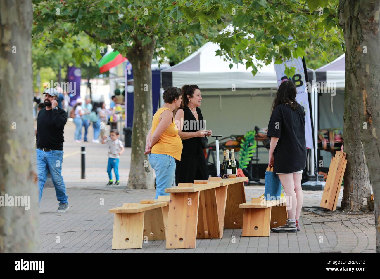 Londres, Royaume-Uni. 20 juillet 2023. 'Bench invasion' de la Compagnie Krak. Dans la performance 'Bench invasion', l'artiste belge Dieter Peter Raphaël Missiaen se déplace dans l'espace public avec dix personnes locales, chacune avec un banc sous le bras, à la recherche de contacts. À un moment inopiné, ils installent des bancs et invitent activement les gens à s’asseoir devant eux. De cette façon, il (re)connecte les gens. Le Festival d'ensemble est un festival de quatre jours de théâtre, de cirque, de danse, de musique et d'art numérique gratuits au Royal Victoria Dock. Ensemble Festival explore les thèmes de l'écologie, de la vie moderne et de la reconnexion, et comprend deux jours de pop-up per Banque D'Images
