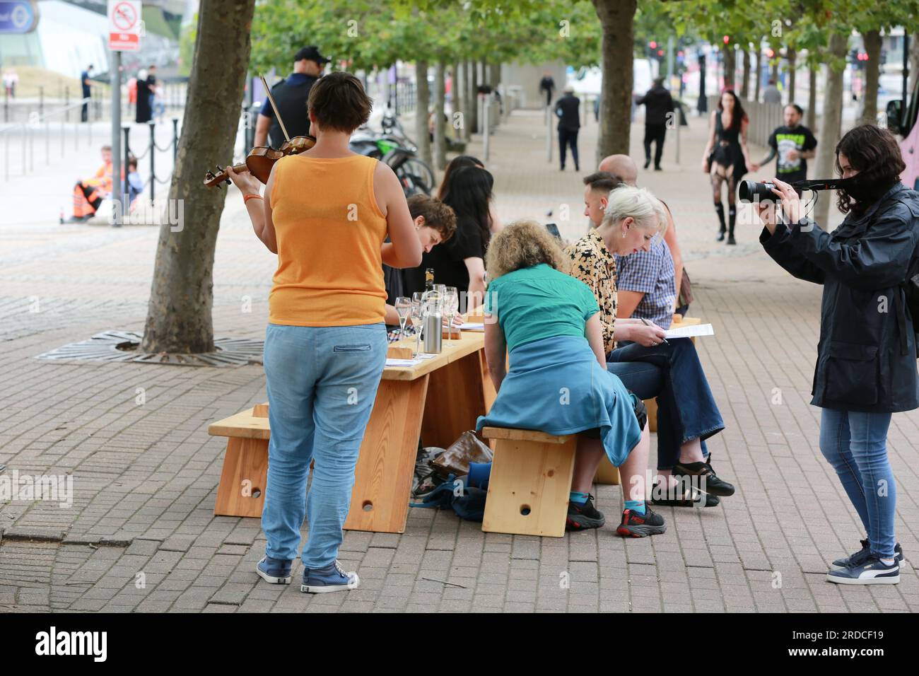 Londres, Royaume-Uni. 20 juillet 2023. 'Bench invasion' de la Compagnie Krak. Dans la performance 'Bench invasion', l'artiste belge Dieter Peter Raphaël Missiaen se déplace dans l'espace public avec dix personnes locales, chacune avec un banc sous le bras, à la recherche de contacts. À un moment inopiné, ils installent des bancs et invitent activement les gens à s’asseoir devant eux. De cette façon, il (re)connecte les gens. Le Festival d'ensemble est un festival de quatre jours de théâtre, de cirque, de danse, de musique et d'art numérique gratuits au Royal Victoria Dock. Ensemble Festival explore les thèmes de l'écologie, de la vie moderne et de la reconnexion, et comprend deux jours de pop-up per Banque D'Images