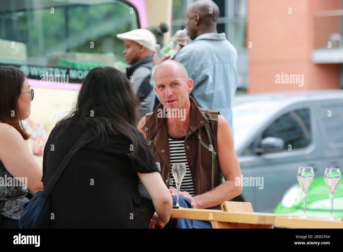 Londres, Royaume-Uni. 20 juillet 2023. 'Bench invasion' de la Compagnie Krak. Dans la performance 'Bench invasion', l'artiste belge Dieter Peter Raphaël Missiaen se déplace dans l'espace public avec dix personnes locales, chacune avec un banc sous le bras, à la recherche de contacts. À un moment inopiné, ils installent des bancs et invitent activement les gens à s’asseoir devant eux. De cette façon, il (re)connecte les gens. Le Festival d'ensemble est un festival de quatre jours de théâtre, de cirque, de danse, de musique et d'art numérique gratuits au Royal Victoria Dock. Ensemble Festival explore les thèmes de l'écologie, de la vie moderne et de la reconnexion, et comprend deux jours de pop-up per Banque D'Images