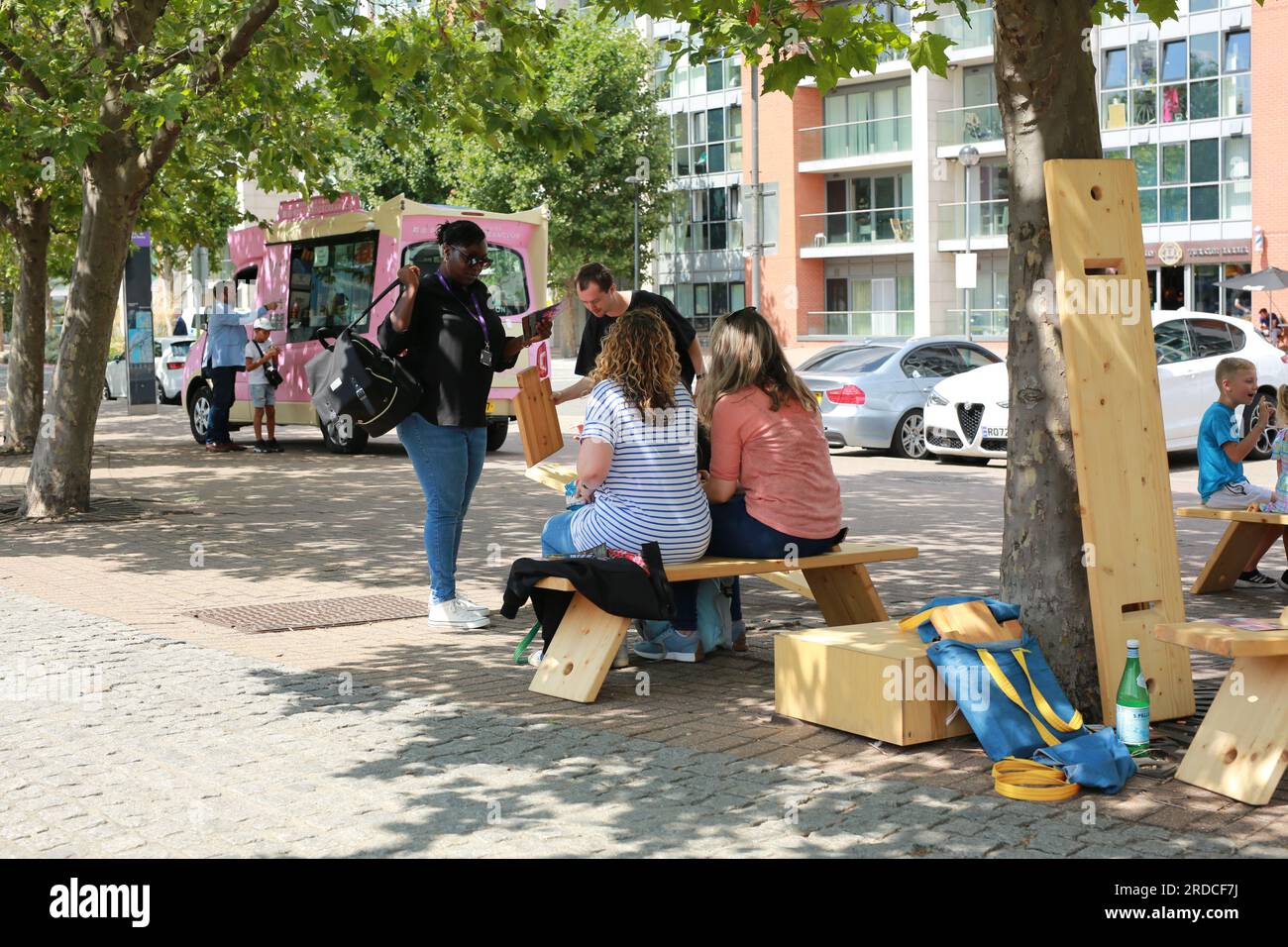 Londres, Royaume-Uni. 20 juillet 2023. 'Bench invasion' de la Compagnie Krak. Dans la performance 'Bench invasion', l'artiste belge Dieter Peter Raphaël Missiaen se déplace dans l'espace public avec dix personnes locales, chacune avec un banc sous le bras, à la recherche de contacts. À un moment inopiné, ils installent des bancs et invitent activement les gens à s’asseoir devant eux. De cette façon, il (re)connecte les gens. Le Festival d'ensemble est un festival de quatre jours de théâtre, de cirque, de danse, de musique et d'art numérique gratuits au Royal Victoria Dock. Ensemble Festival explore les thèmes de l'écologie, de la vie moderne et de la reconnexion, et comprend deux jours de pop-up per Banque D'Images