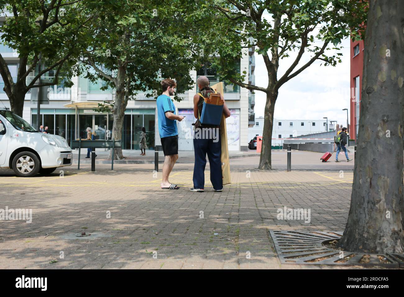 Londres, Royaume-Uni. 20 juillet 2023. 'Bench invasion' de la Compagnie Krak. Dans la performance 'Bench invasion', l'artiste belge Dieter Peter Raphaël Missiaen se déplace dans l'espace public avec dix personnes locales, chacune avec un banc sous le bras, à la recherche de contacts. À un moment inopiné, ils installent des bancs et invitent activement les gens à s’asseoir devant eux. De cette façon, il (re)connecte les gens. Le Festival d'ensemble est un festival de quatre jours de théâtre, de cirque, de danse, de musique et d'art numérique gratuits au Royal Victoria Dock. Ensemble Festival explore les thèmes de l'écologie, de la vie moderne et de la reconnexion, et comprend deux jours de pop-up per Banque D'Images