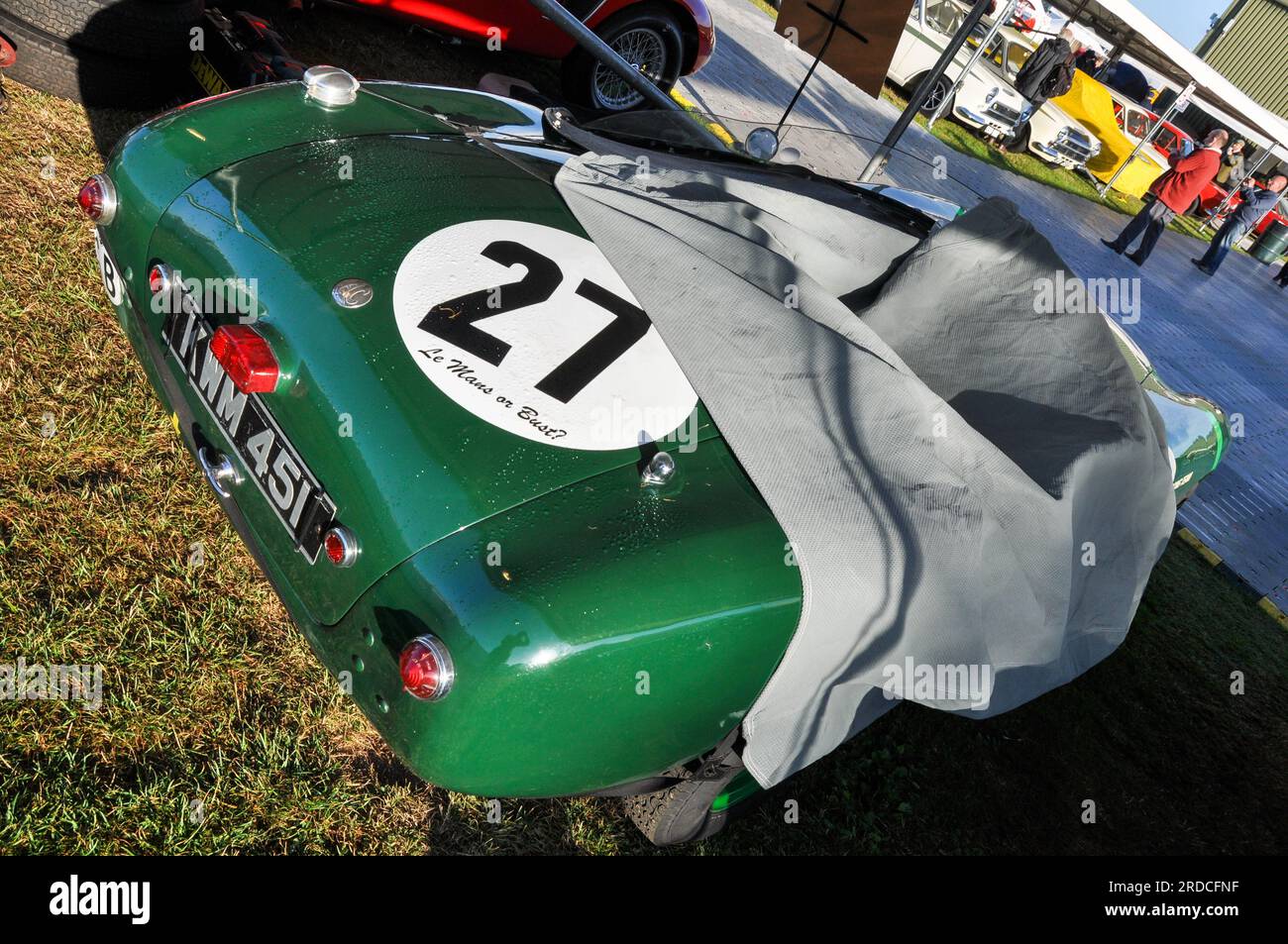 Slogan le Mans ou buste sur une voiture de course automobile classique AC Ace verte. Couvercle partiellement retiré. Goodwood Revival. AC Cars Ltd Feuille anti-poussière. Numéro 27 Banque D'Images