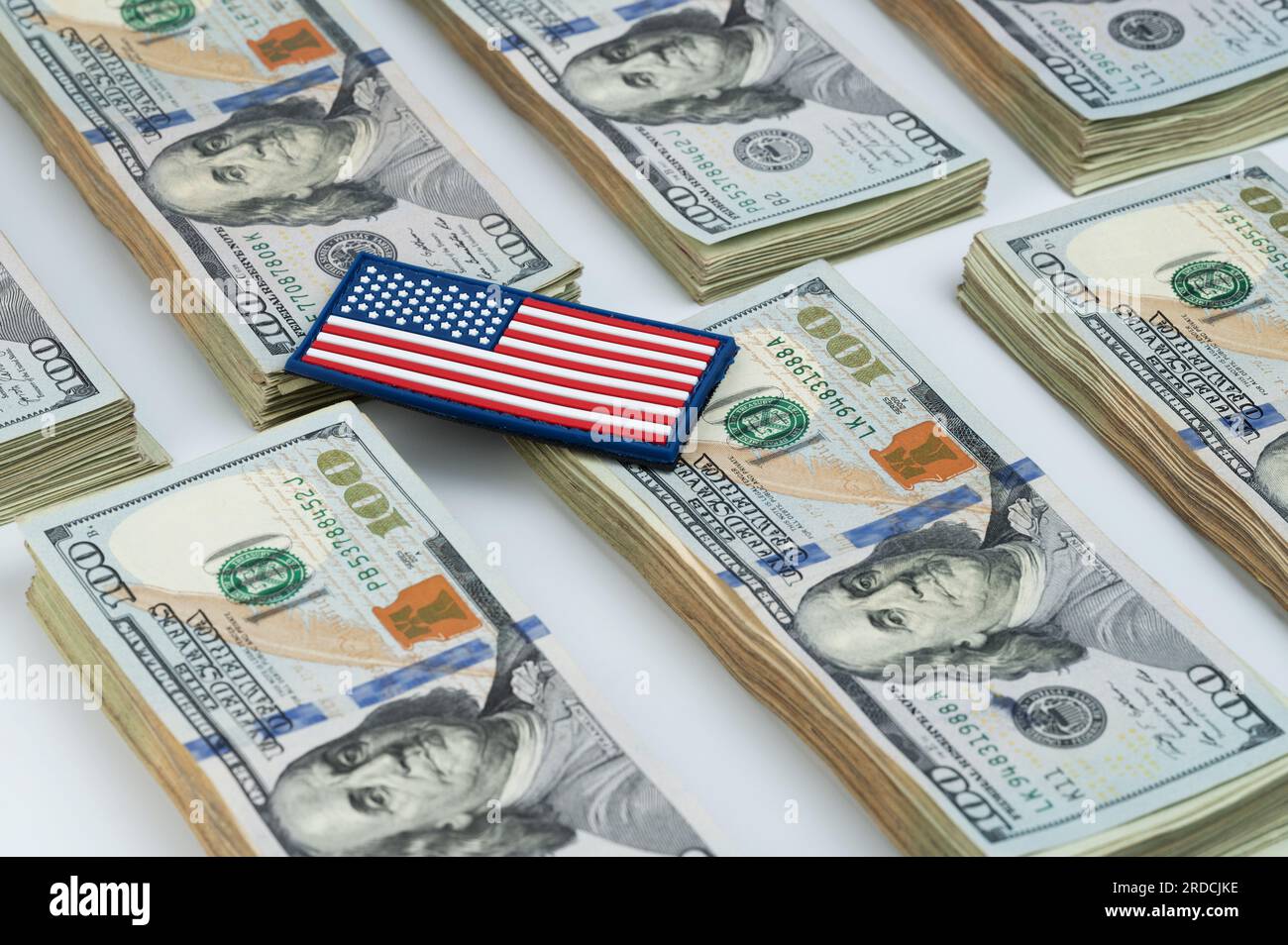 Drapeau américain sur 100 piles de billets de dollar américain reposent sur fond blanc de studio Banque D'Images
