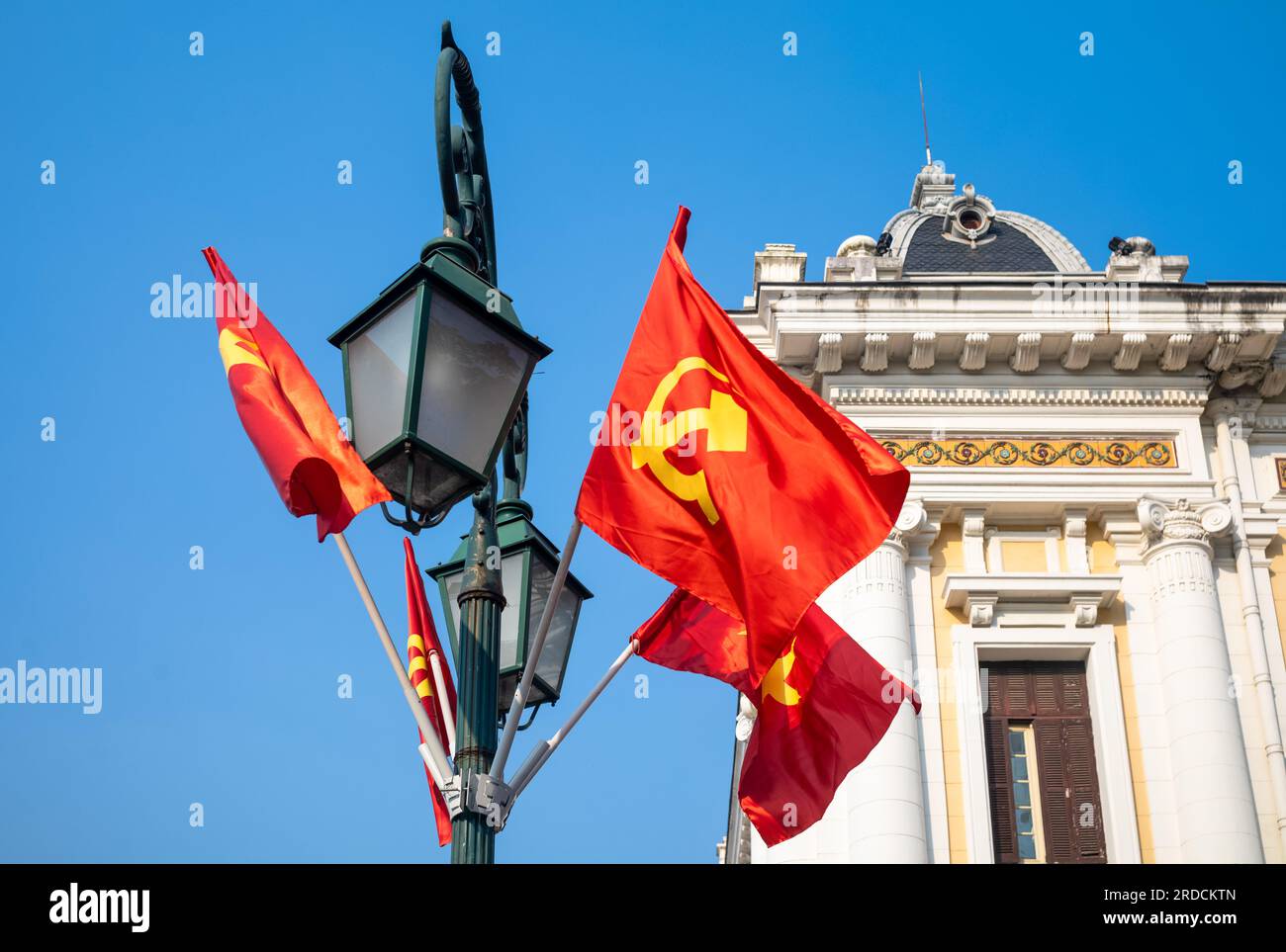 Le marteau et la faucille communistes et les drapeaux vietnamiens étoilés d'or volent d'un lampadaire à l'extérieur de l'Opéra de Hanoi, à Hanoi, Vietnam Banque D'Images