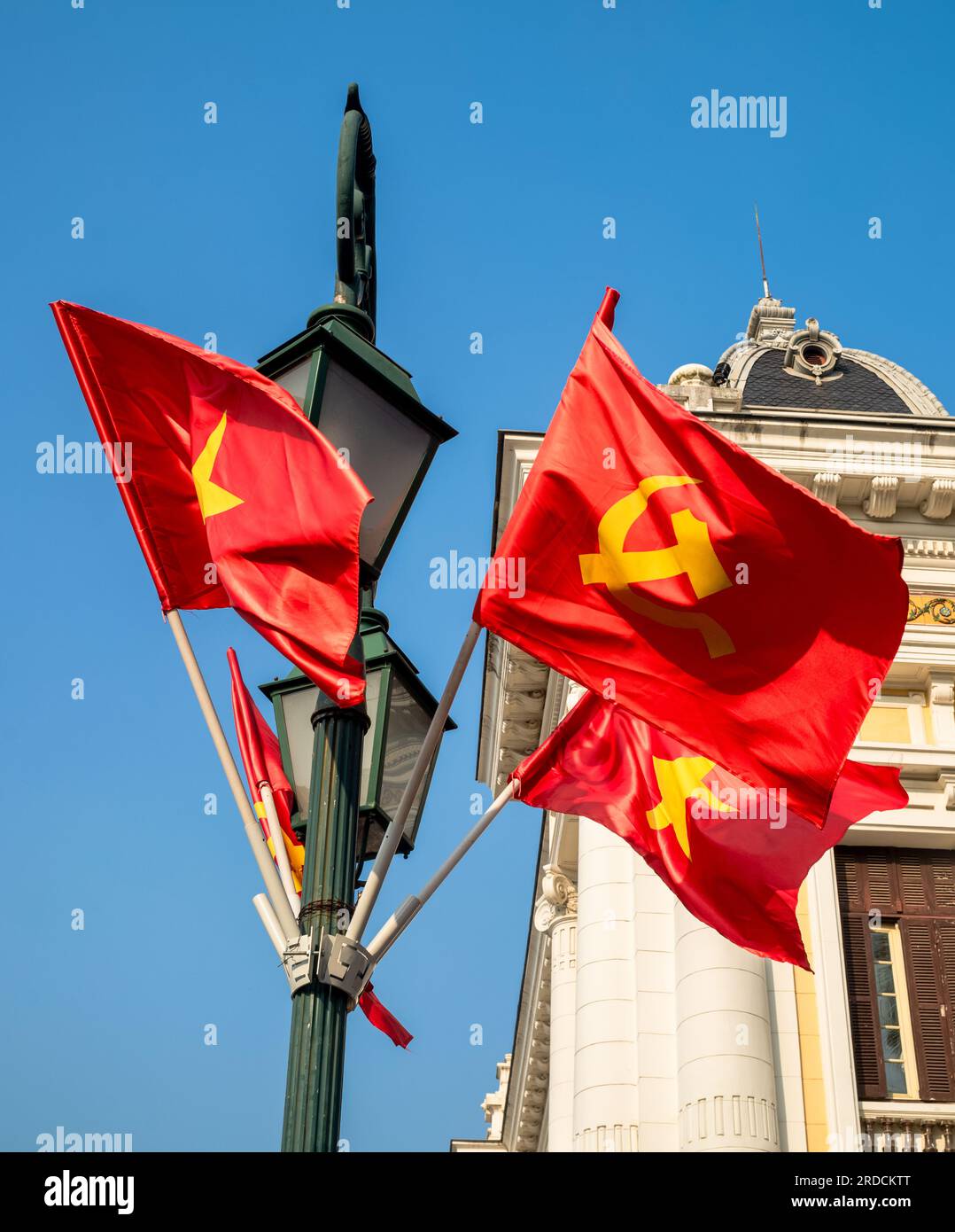 Le marteau et la faucille communistes et les drapeaux vietnamiens étoilés d'or volent d'un lampadaire à l'extérieur de l'Opéra de Hanoi, à Hanoi, Vietnam Banque D'Images