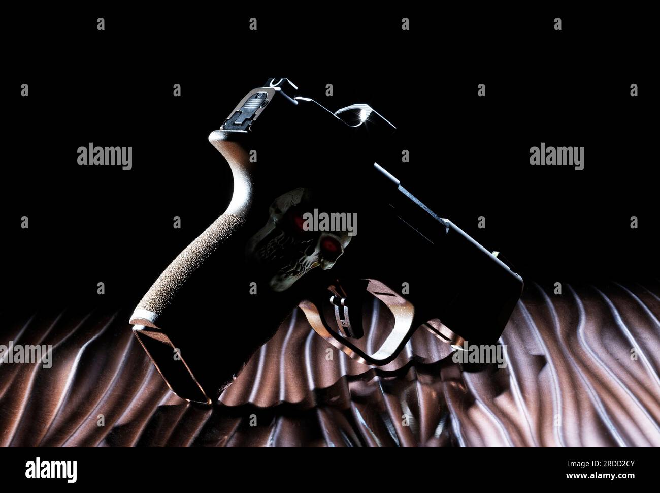 Silhouette de pistolet sur une surface ondulée avec un crâne humain et des yeux rouges sur sa poignée Banque D'Images