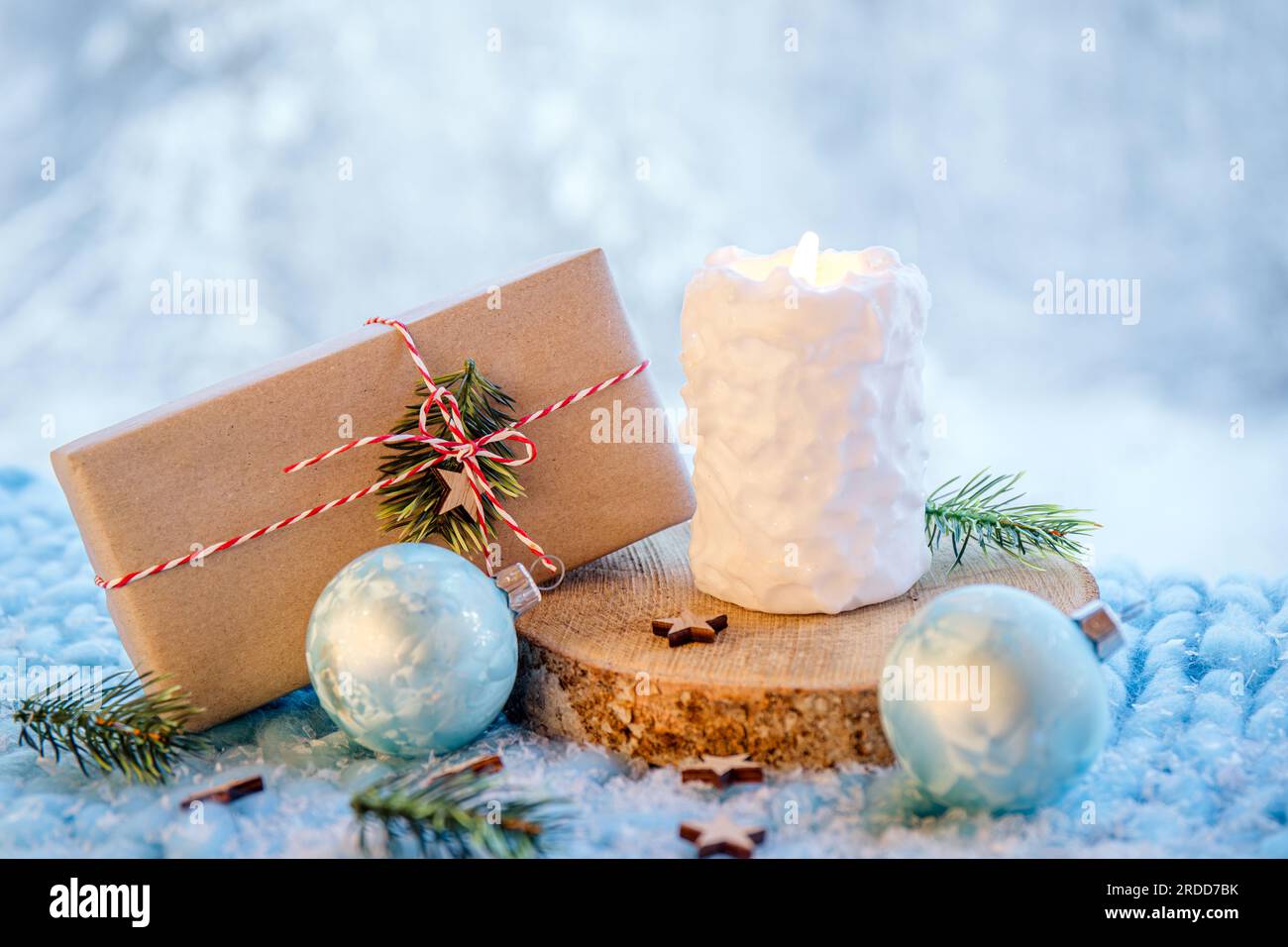 Fond des produits de Noël. Bougie de motif boule de neige blanche brûlant, cadeau de Noël enveloppé dans du papier brun avec ficelle blanche et rouge. Banque D'Images