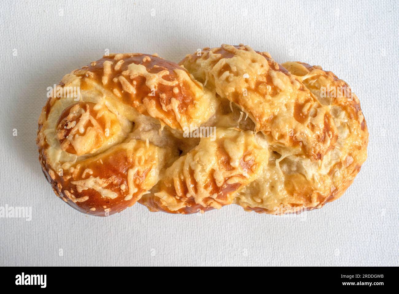 Pain bretzel moelleux recouvert de fromage fondu, parfait pour une collation savoureuse et satisfaisante. Capturée sur fond blanc pour une délicieuse présentation. Banque D'Images