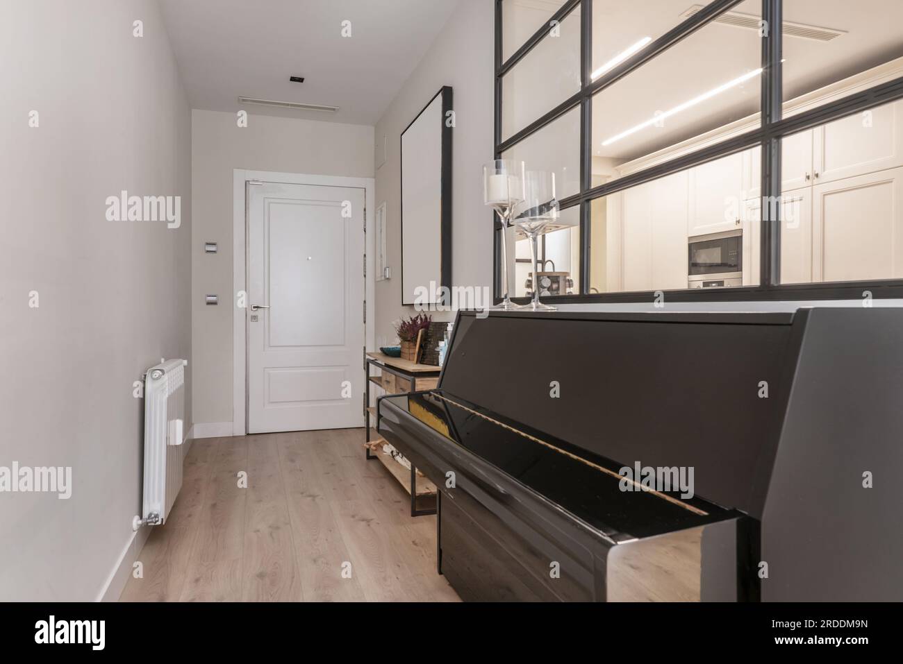 Hall d'entrée d'une maison résidentielle avec piano dans le couloir et porte d'accès blindée laquée en blanc Banque D'Images