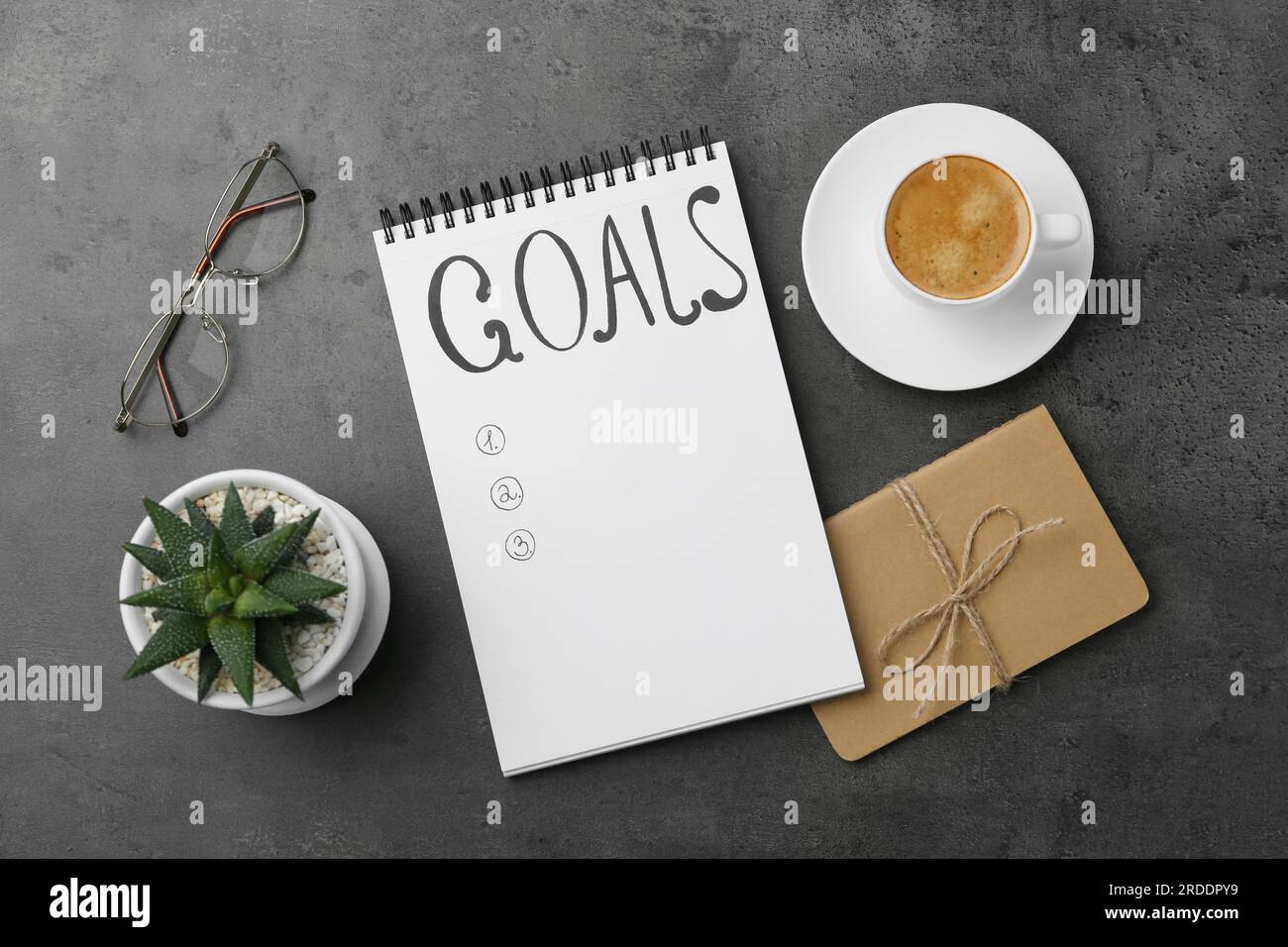 Concept de planification. Liste vide d'objectifs dans le cahier et le café sur fond gris, plat Banque D'Images