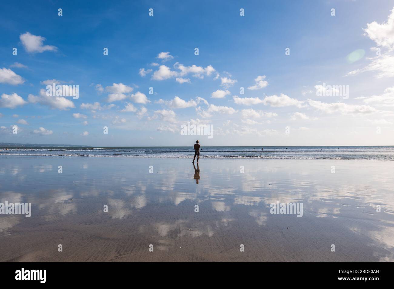 Un homme debout sur la plage de kuta dans le sud de Bali, Indonésie. Banque D'Images