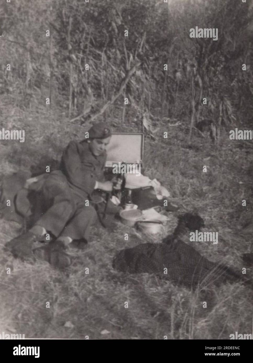 rare photo de vie militaire de la seconde guerre mondiale ( ww2) un soldat est allongé sur l'herbe pour se reposer. Il est en train de déjeuner. mangez de la nourriture froide dans la zone de guerre. Banque D'Images