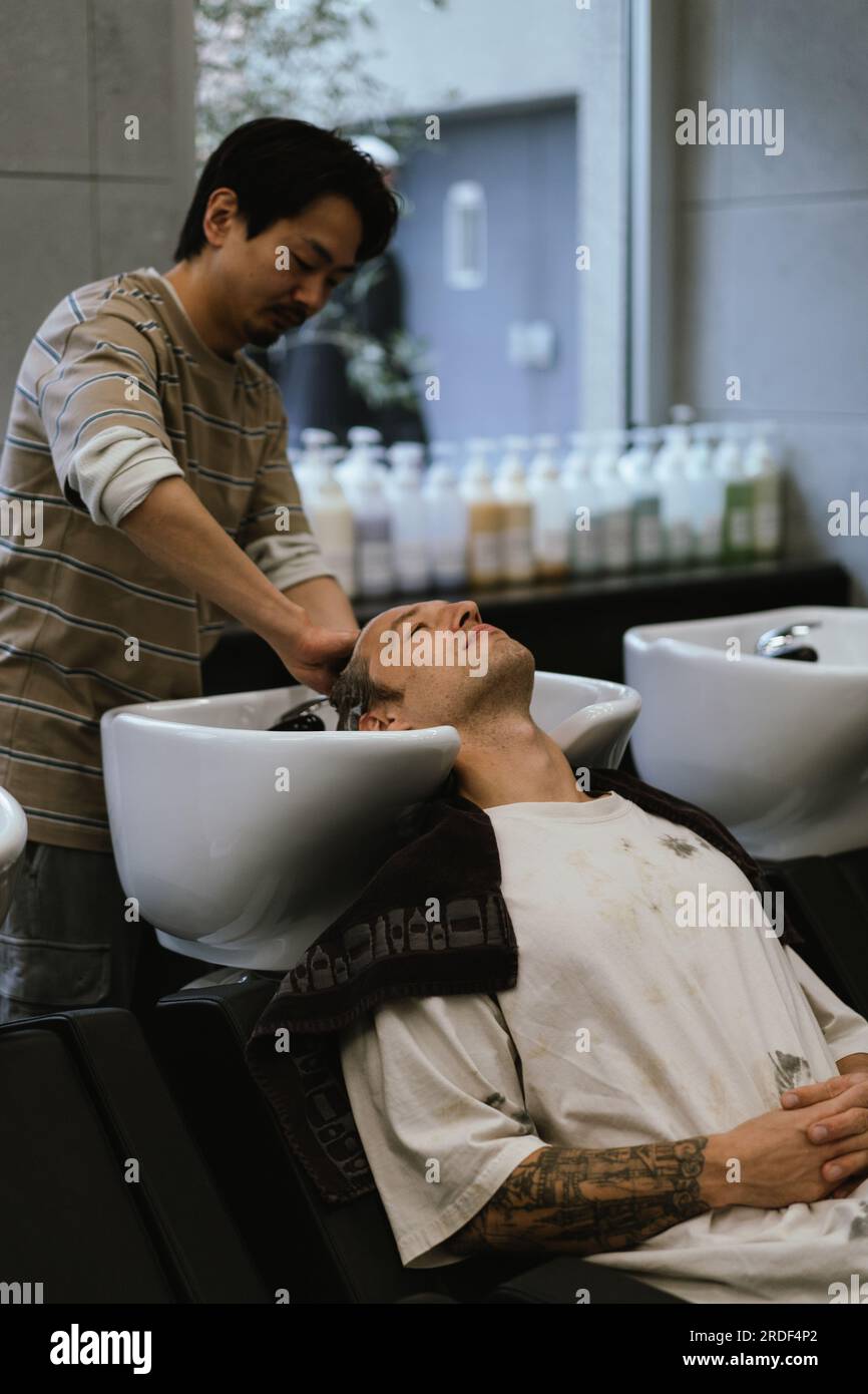 Coiffeur laver les cheveux à bel homme dans le salon de beauté. Banque D'Images