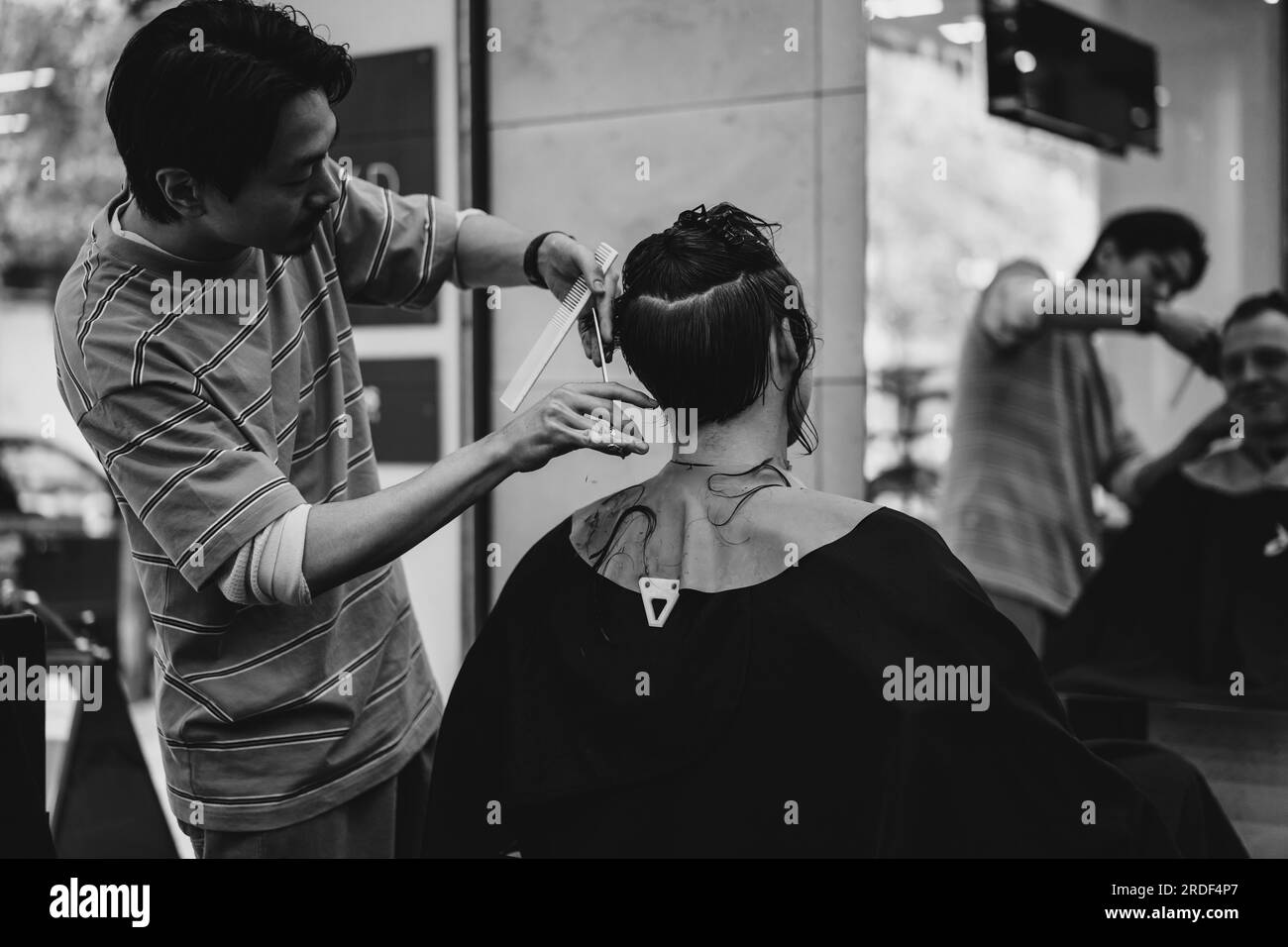 Un barbier japonais coupe les cheveux d'un client dans un salon de coiffure. Banque D'Images