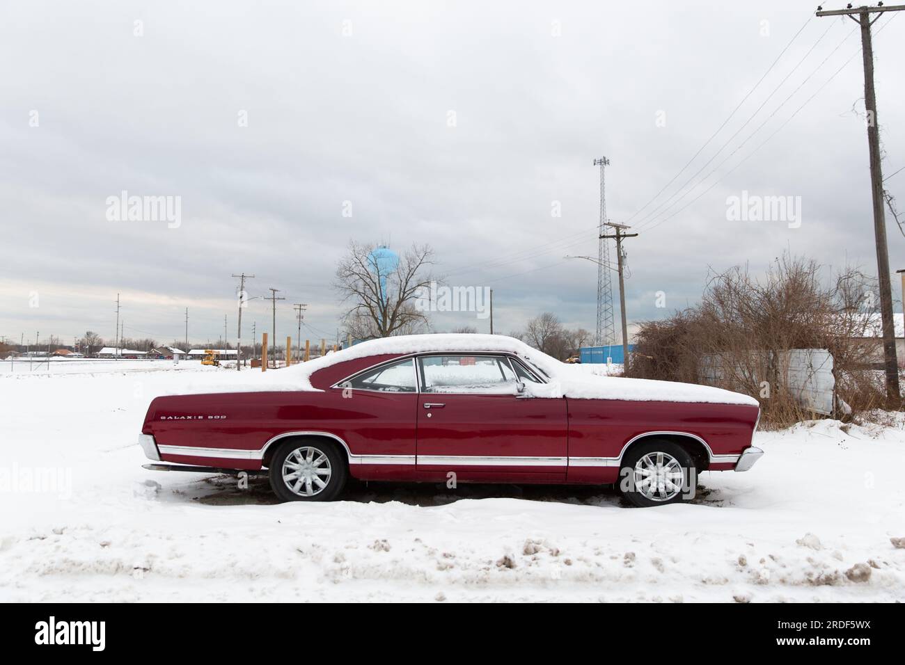 Une voiture rouge d'époque se trouve sur un paysage Americana couvert de neige Banque D'Images
