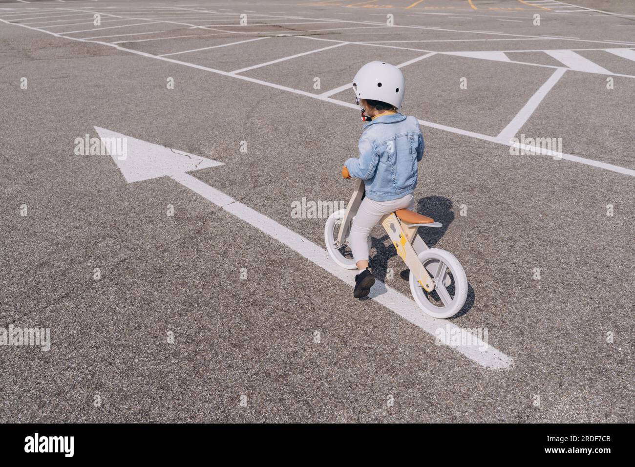 ?aucasian fille préscolaire chevauchant vélo d'équilibre en bois sur la route asphaltée Banque D'Images