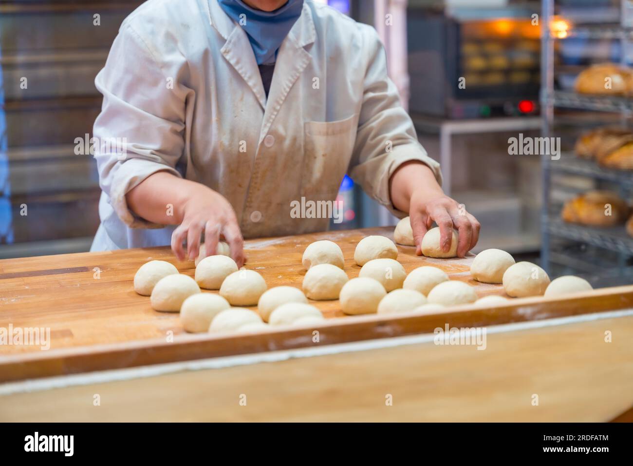 Femme employée de machine à pain dans l'atelier de boulangerie artisanale préparant la pâte dans un cercle Banque D'Images