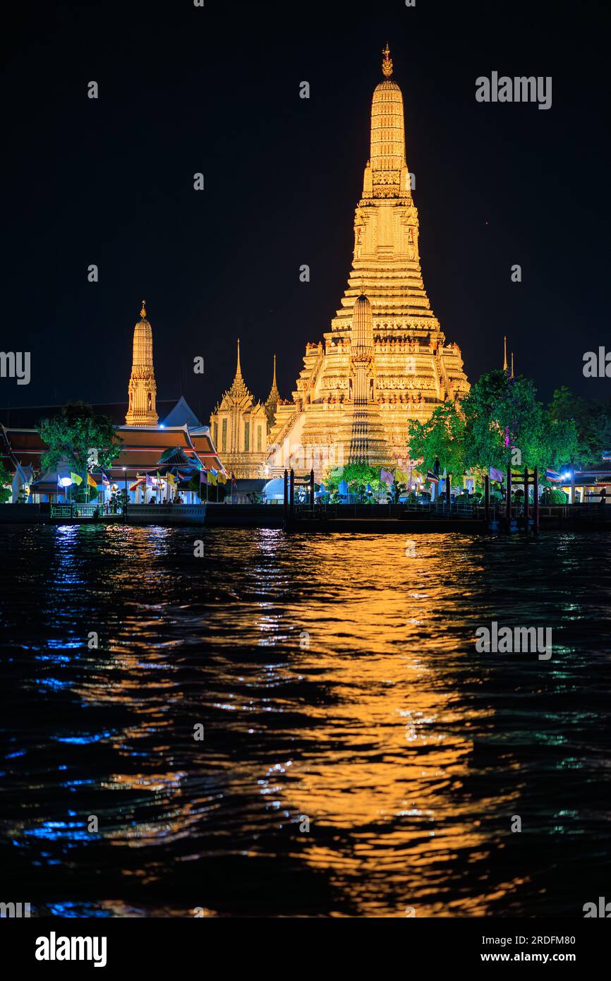 Illuminé vieux temple bouddhiste Wat Arun réfléchissant sur la rivière Chao Phraya à Bangkok Banque D'Images