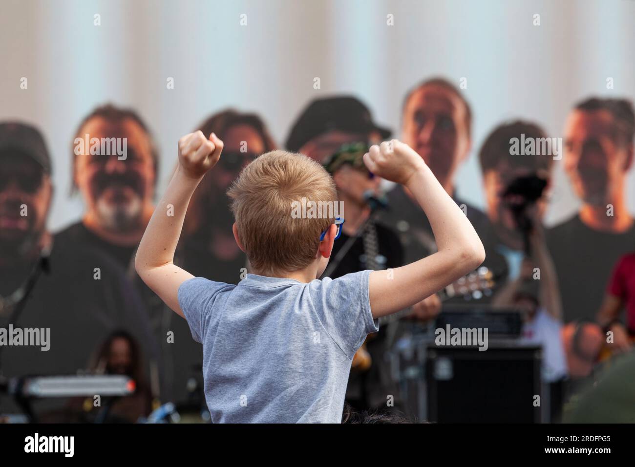 Gattatico, Reggio Emilia, Italie - 25 avril 2023 : vue arrière de l'enfant tendant les mains vers le haut lors d'un concert pour la commémoration de la Journée de la libération en Italie Banque D'Images