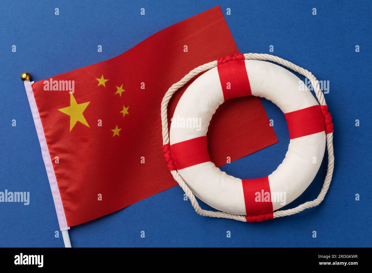 Drapeau chinois et bouée de sauvetage sur fond bleu, un concept sur le thème de l'aide de la Chine Banque D'Images