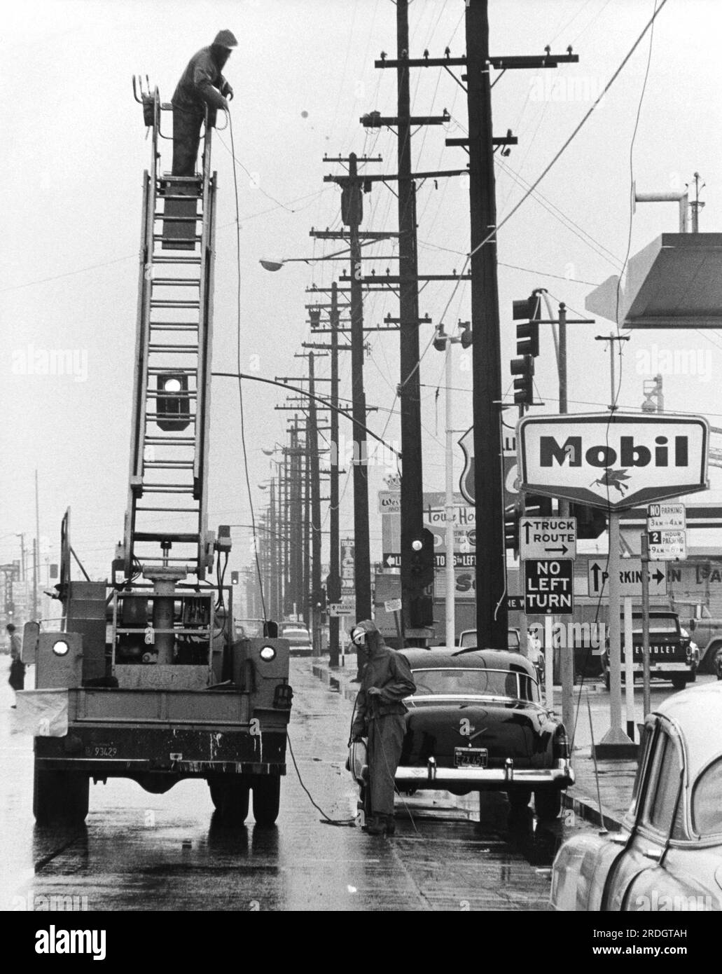 Californie : c. 1955 Une équipe de service public travaillant sur une sreet de ville un jour de pluie. Banque D'Images
