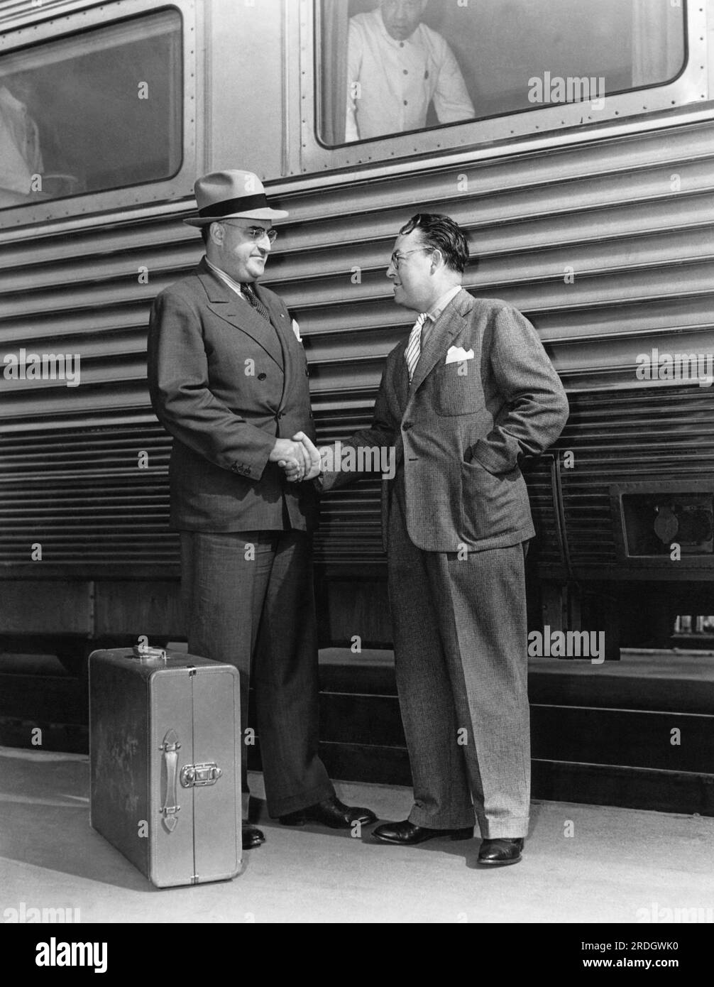 États-Unis : c. 1944 deux hommes en costume se serrent la main à un quai de gare. Banque D'Images