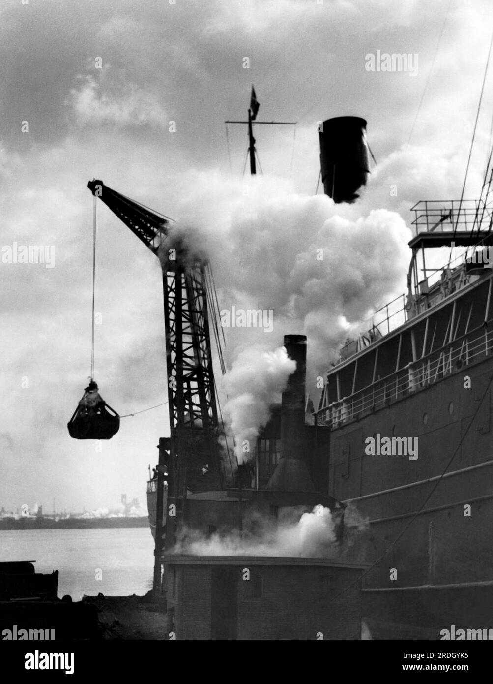 New York, New York : c. 1925 grue chargeant du charbon sur un navire à vapeur. Banque D'Images