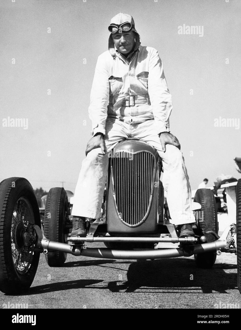 États-Unis : c. 1936 Un pilote est assis à cheval sur le capot de sa voiture de course. Banque D'Images