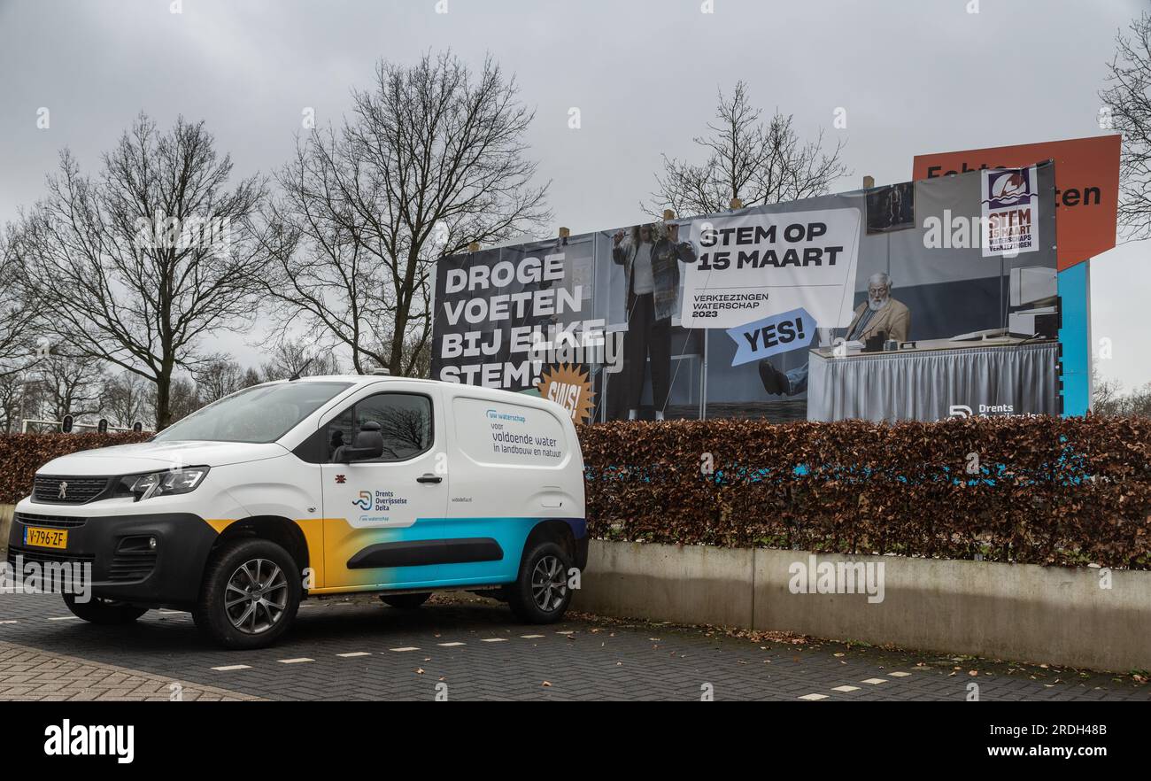 Zwolle, pays-Bas - 17 février 2023 : une voiture de société garée devant un panneau publicitaire pour promouvoir les prochaines élections hollandaises en matière d'aqueduc. Néerlandais : Banque D'Images