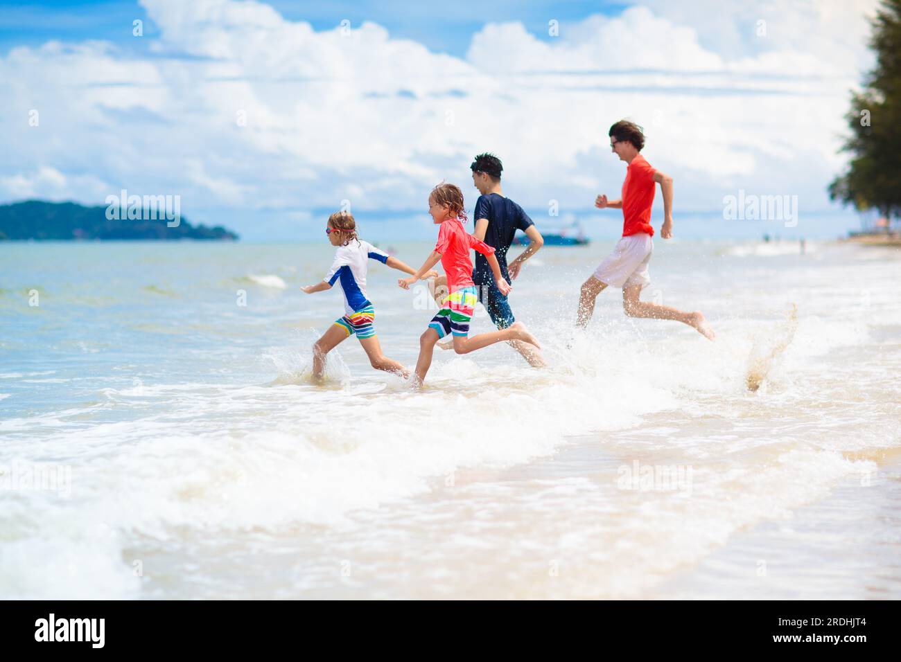 Enfant jouant sur la plage tropicale. Groupe de garçons courant au bord de la mer. Vacances d'été en famille. Voyage et camping avec les enfants. Banque D'Images