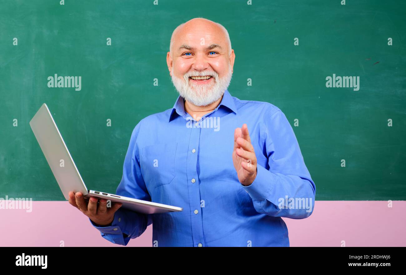 Enseignant souriant avec ordinateur portable devant le tableau noir dans la salle de classe. Professeur donnant des leçons aux élèves. E-learning à l'université. Enseignant masculin avec Banque D'Images