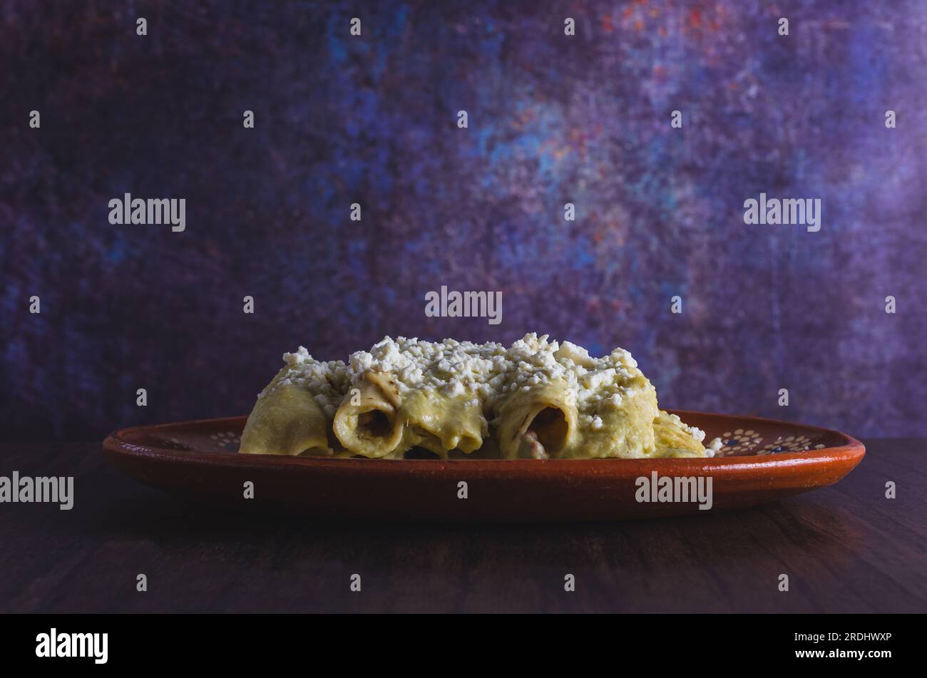 Green Enchiladas servi dans un plat en argile sur une table en bois. Cuisine mexicaine typique. Arrière-plan coloré. Banque D'Images