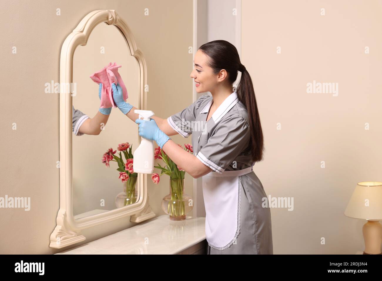 Jeune femme de chambre nettoyant la coiffeuse dans la chambre d'hôtel Photo  Stock - Alamy