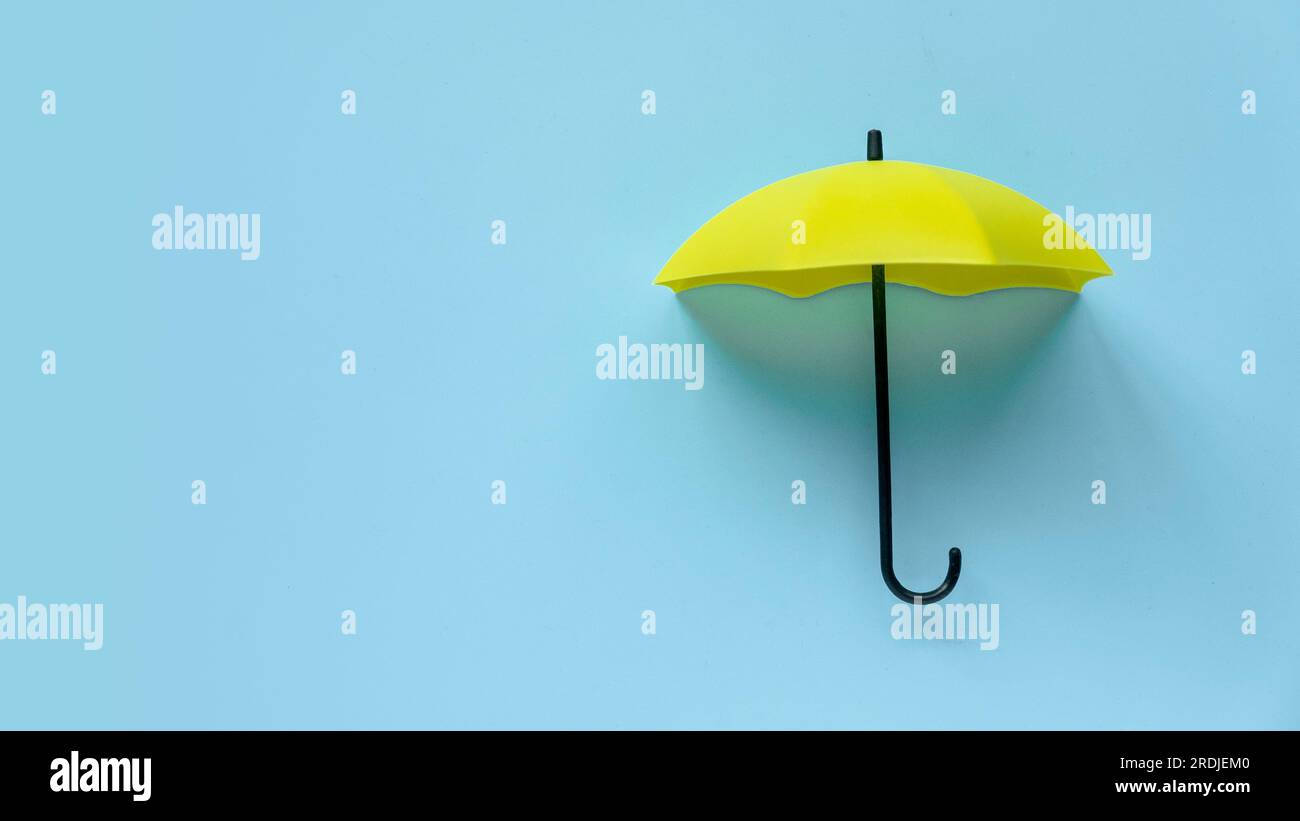 Parapluie jaune sur fond bleu. Bannière avec espace de copie. Banque D'Images