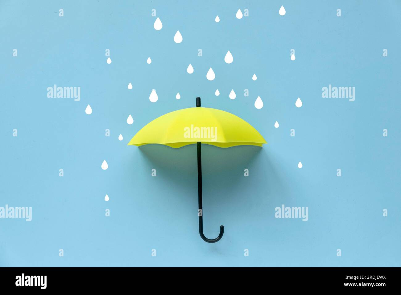 Parapluie jaune et goutte de pluie sur un fond bleu. Banque D'Images