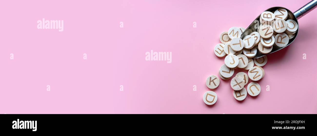 Cercle alphabet en bois sur fond rose pastel avec espace de copie. Banque D'Images