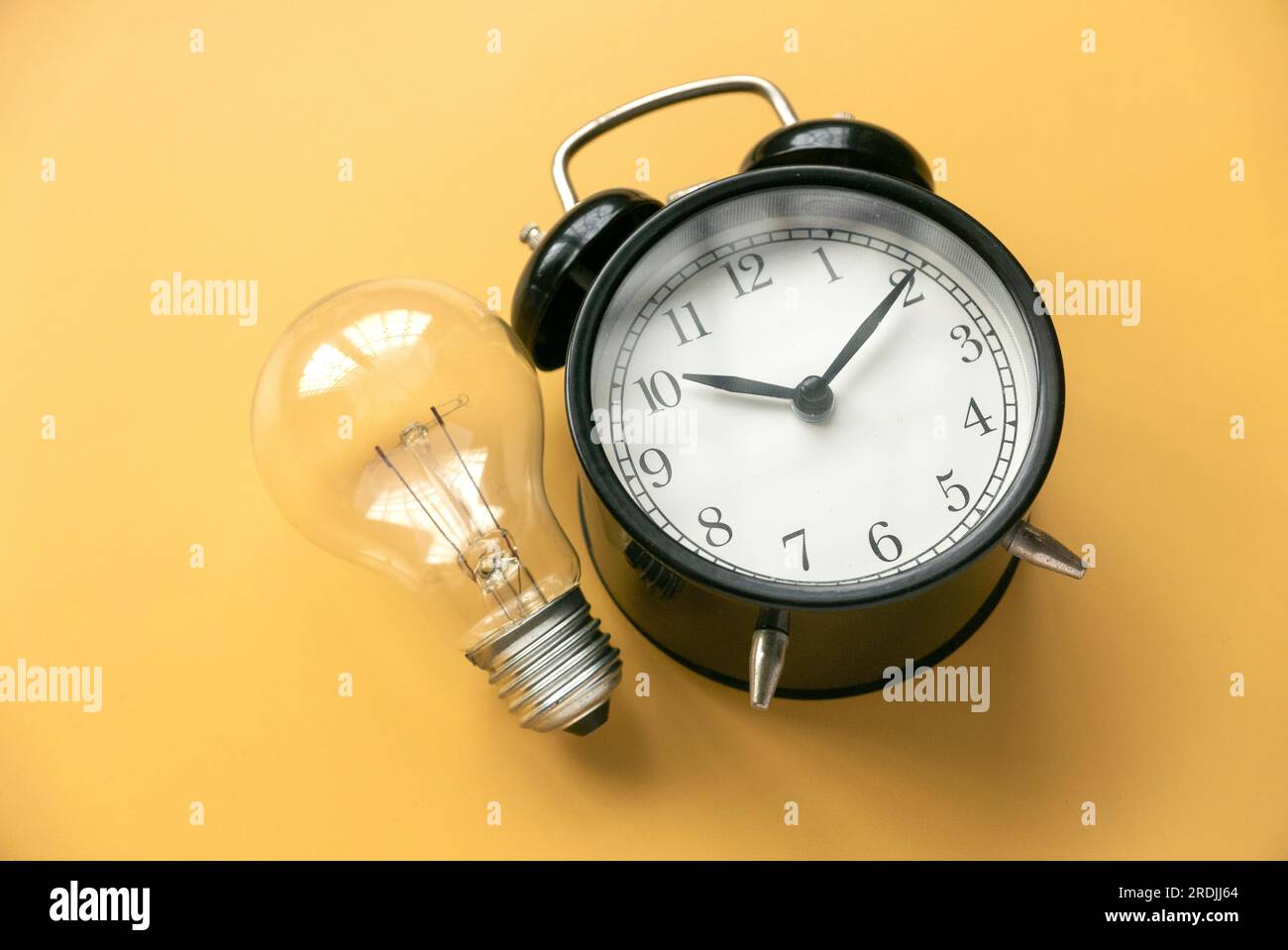 Concepts d'inspiration de créativité, idées de planification. Ampoule et réveil sur fond jaune. Banque D'Images