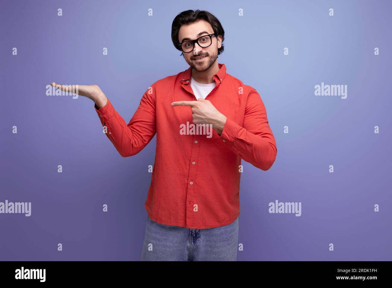 bel homme millénaire brunette de 35 ans avec des cheveux magnifiques montre sa main sur le côté Banque D'Images