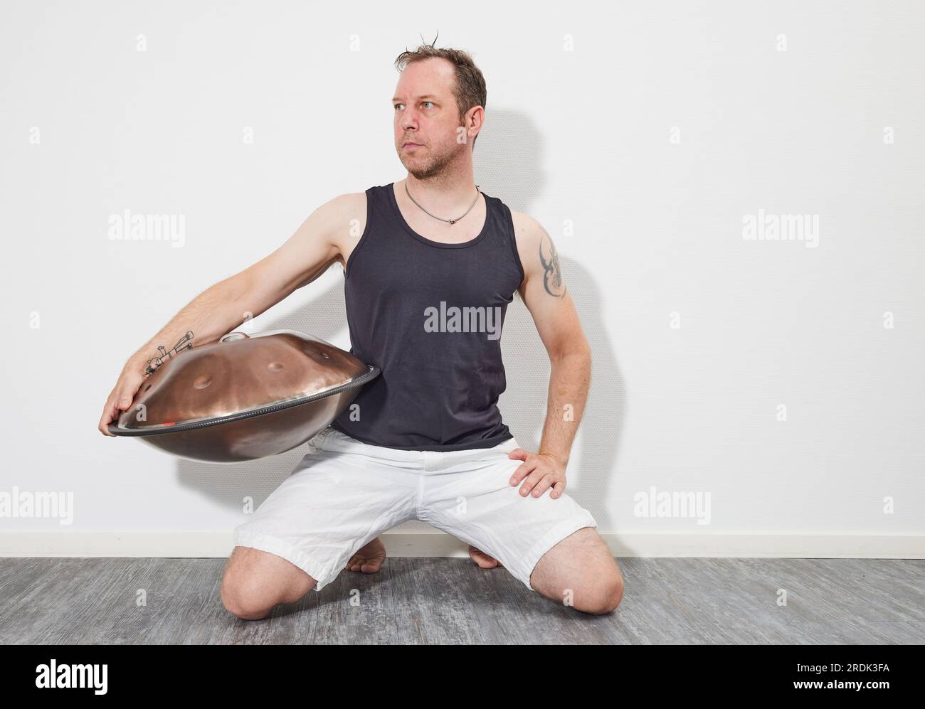 Homme assis sur le sol jouant handpan Banque D'Images