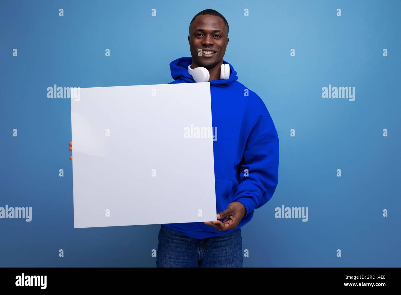 25 ans jeune homme américain montre une affiche de papier avec une maquette pour la publicité sur le fond avec espace de copie Banque D'Images