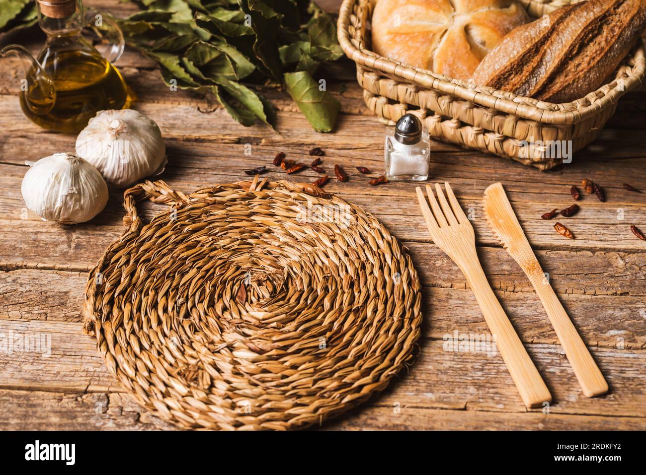 Trépied sur une table rustique en bois avec couverts, pain, ail, sel, poivre de Cayenne et Laurier. Banque D'Images