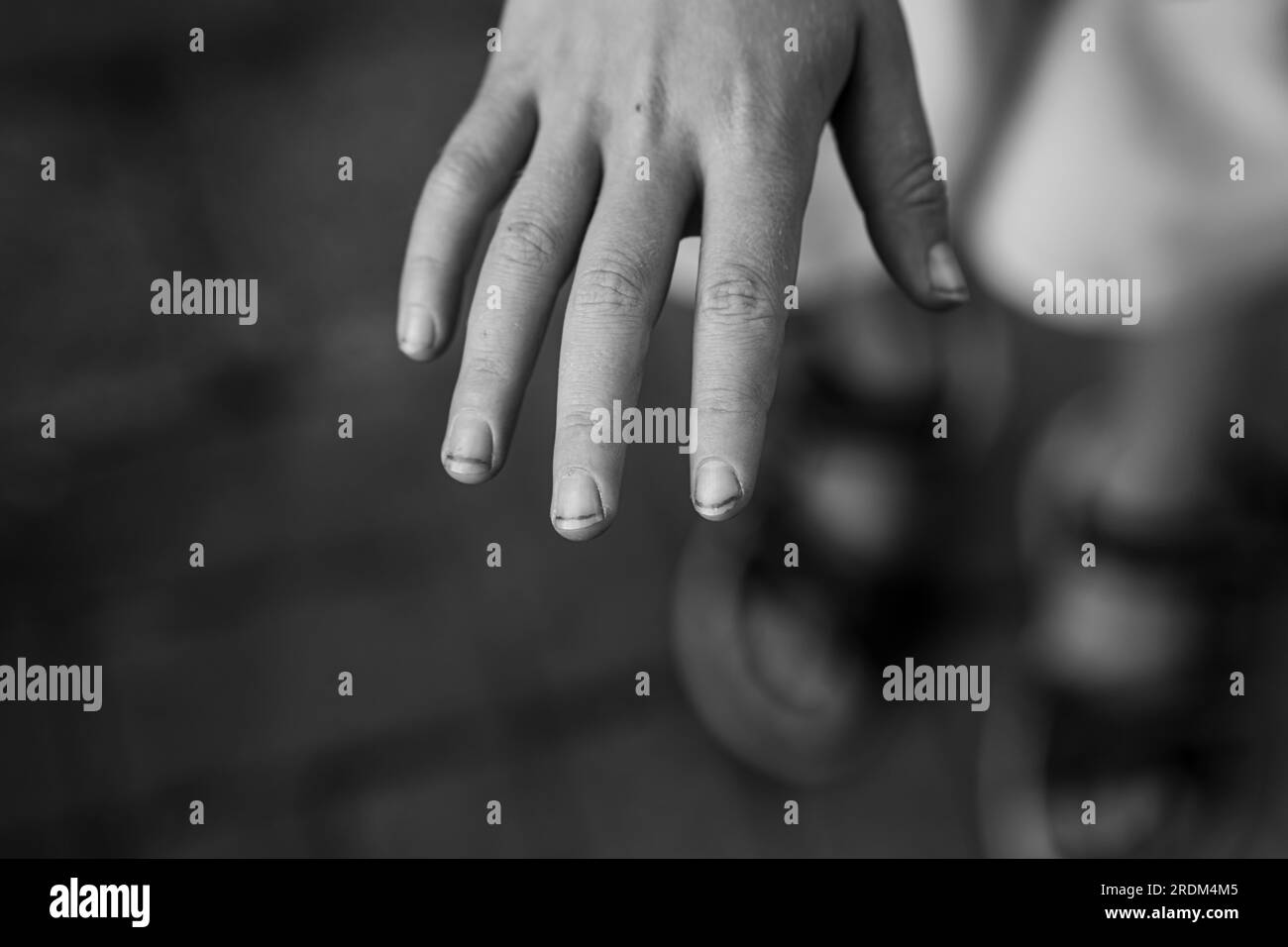 Photo en gros plan des mains du garçon. Les mains d'un garçon de jardin. De longs ongles et de la saleté sous les ongles. Les mains des enfants en désordre. Image en noir et blanc. Banque D'Images