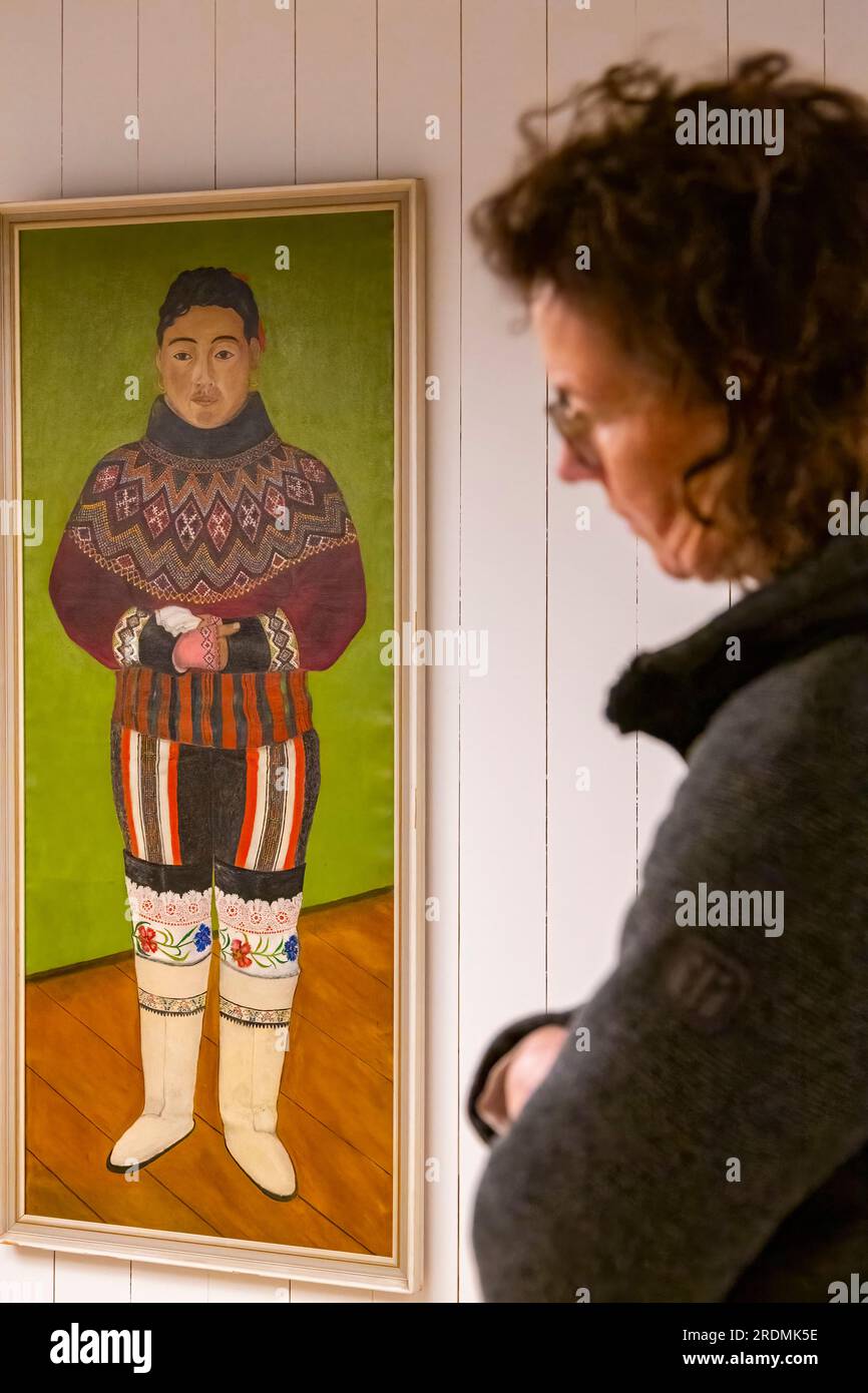Objets exposés au musée de Maniitsoq, dans l'ouest du Groenland en juillet - femme regardant la peinture montrant le costume traditionnel groenlandais Banque D'Images