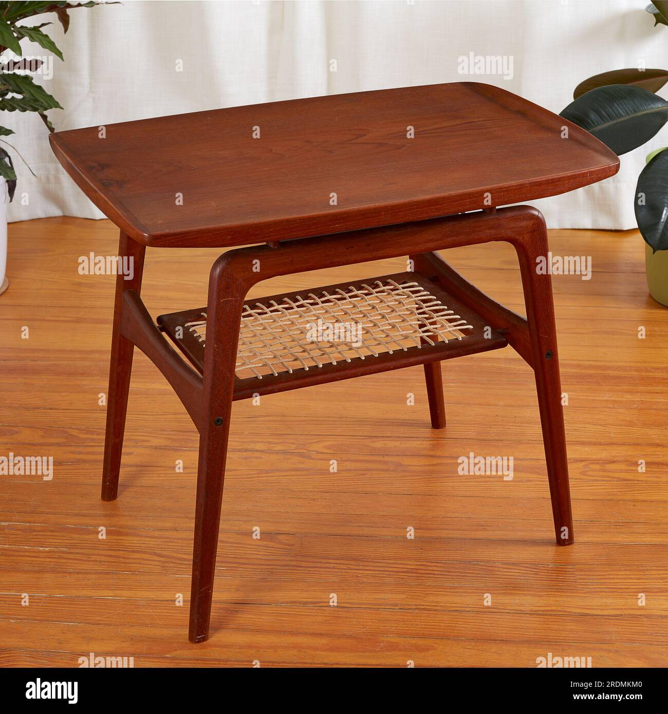 Table d'appoint moderne sculptée du milieu du siècle avec une étagère tissée. Mobilier élégant en teck vintage. Banque D'Images